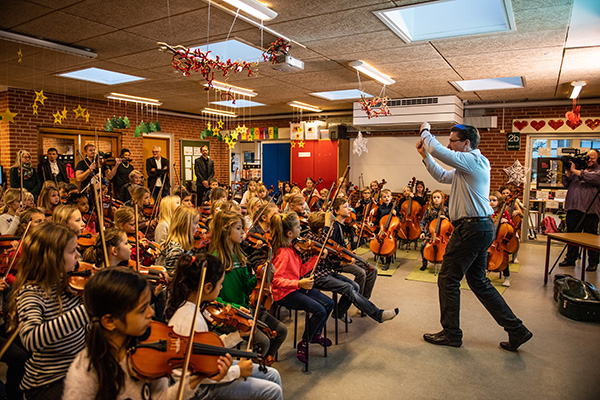 Børneorkester med bl.a. violiner og celloer øver sig under overværelse af inviterede pressefolk