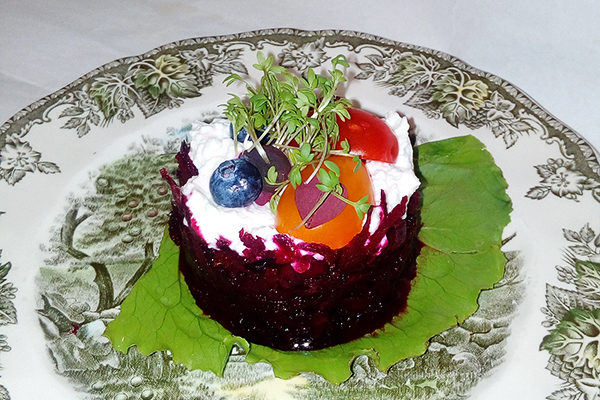 mønstret tallerken med tatar lavet på rødbede og pyntet med bl.a. blåbær